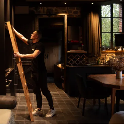 Une équipière Apex manœuvre une échelle en bois dans un intérieur