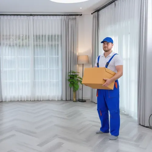 Un intervenant transporte un carton dans une pièce entièrement vidée
