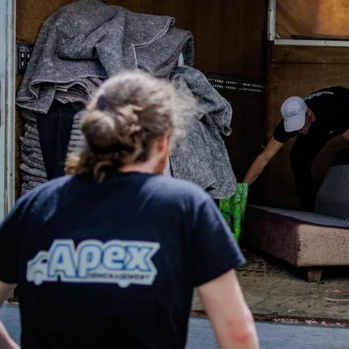 Équipière Apex de dos devant un camion de déménagement en cours de chargement